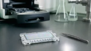 A small glass sequencing flow cell in a clear cradle beside fine tweezers on a laboratory bench